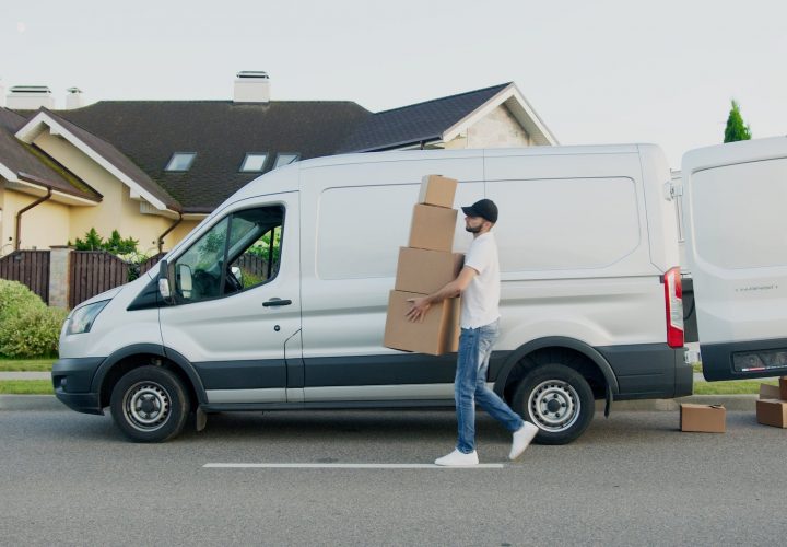 man carrying boxes beside a van